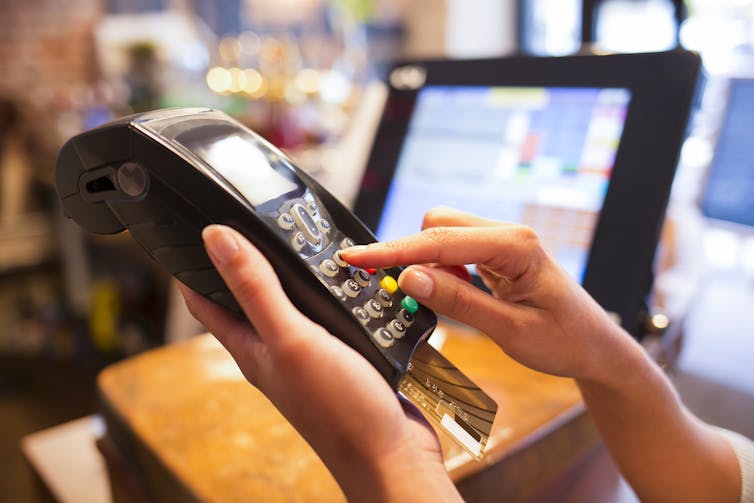 A close-up of a pair of hands using a credit card reader in a store