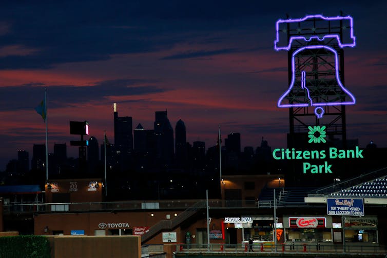 A dark city skyline with a neon sign in the foreground.