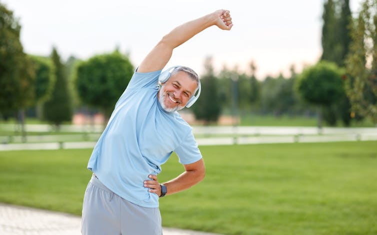 Middle-aged man stretching in a park.