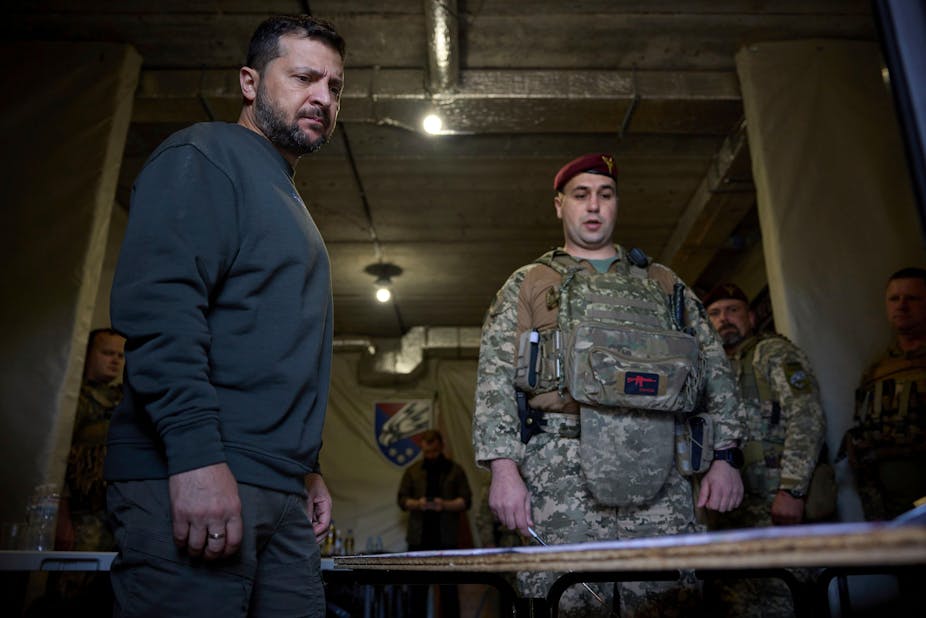 Ukrainian president Volodymyr Zelensky stands next to a soldier as he has a military briefing.