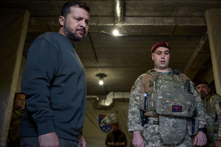 Ukrainian president Volodymyr Zelensky stands next to a soldier as he has a military briefing.