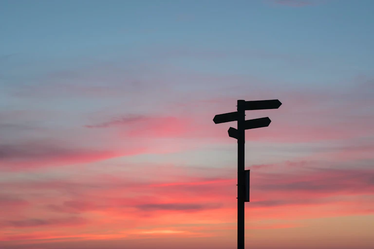 Sign pointing in different directions under a darkening sky.