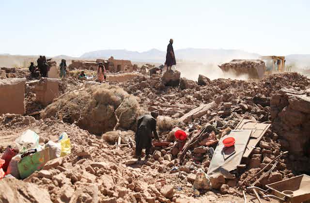 A group of villagers look at what's left of their community after a devastating series of earthquakes.