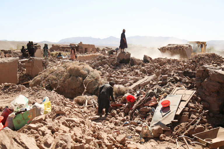 A group of villagers look at what's left of their community after a devastating series of earthquakes.