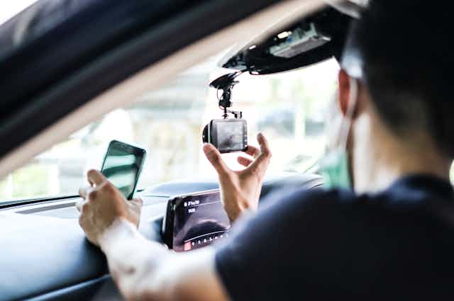 Man adjusting electronic device mounted on car windscreen