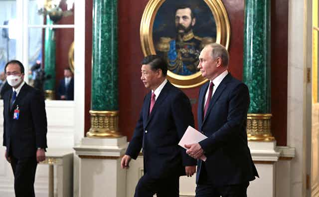 President Xi and President Putin wearing dark blue suits walk together.