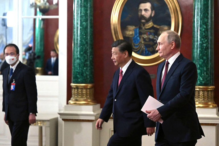 President Xi and President Putin wearing dark blue suits walk together.