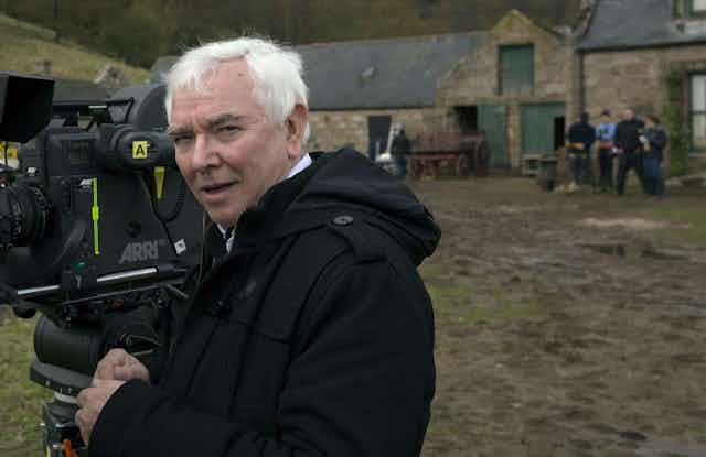 Terence Davies in a field with a film camera. 