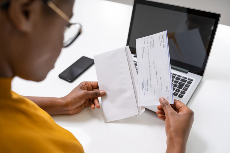 Over-the-shoulder shot of a woman taking a cheque out of an envelope