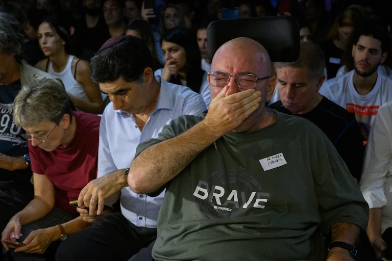 An upset man covering his mouth, surrounded by sad people.