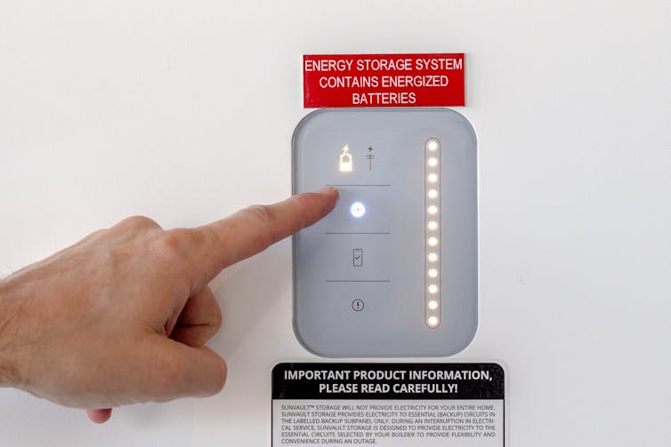 A hand points to a lighted electronic panel.