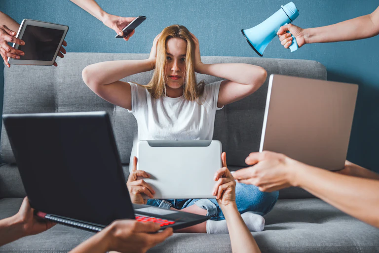 A woman sitting on a sofa covering her ears while people point devices at her.