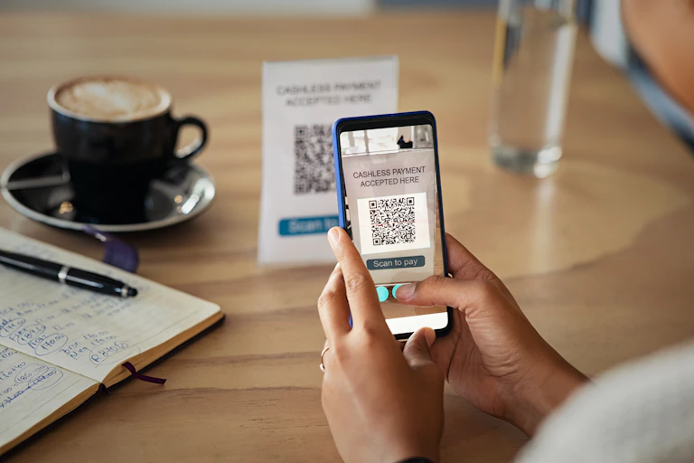 Woman uses phone to make payment for coffee