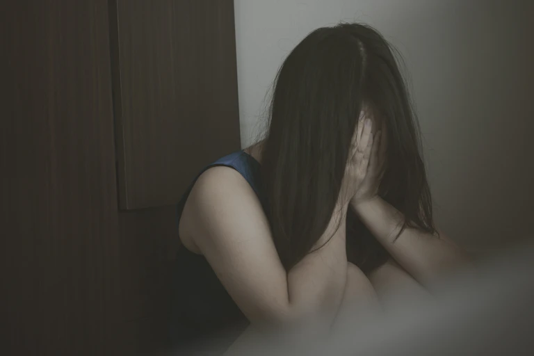 young woman covers face with hands