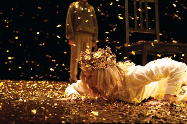 Gold rains down on Cate, in a gold crown.