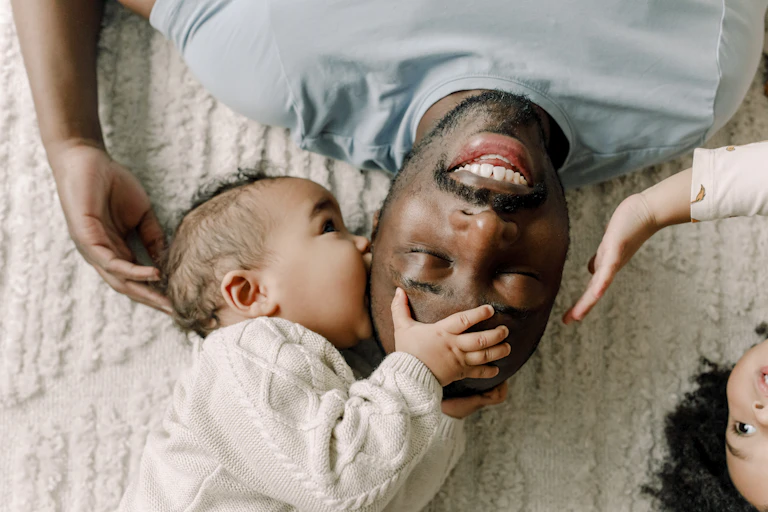 Man, baby and young child lying down and touching each other affectionately