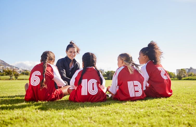 Young female coach with group of girls in football kit