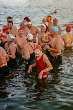 Photo d’un groupe de baigneurs avec au premier plan une dame âgée souriante.