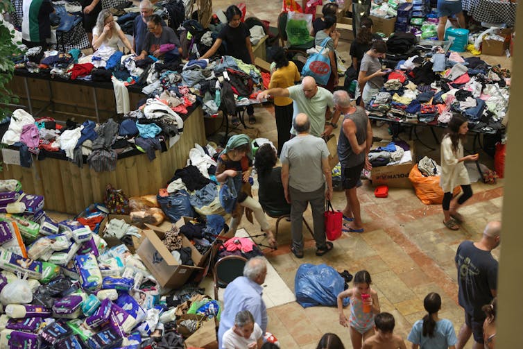 People mill around heaps of donated clothing and other essential goods.