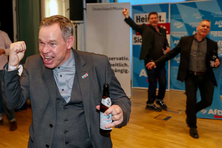 Three men dancing and holding beers.