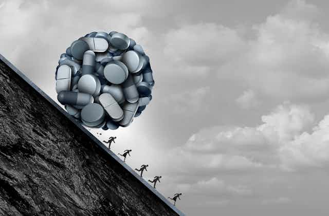 Black and white illustration of a ball of pills rolling down a hill, about to roll over small human figures