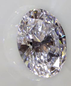 A circular white diamond sitting on a white surface.