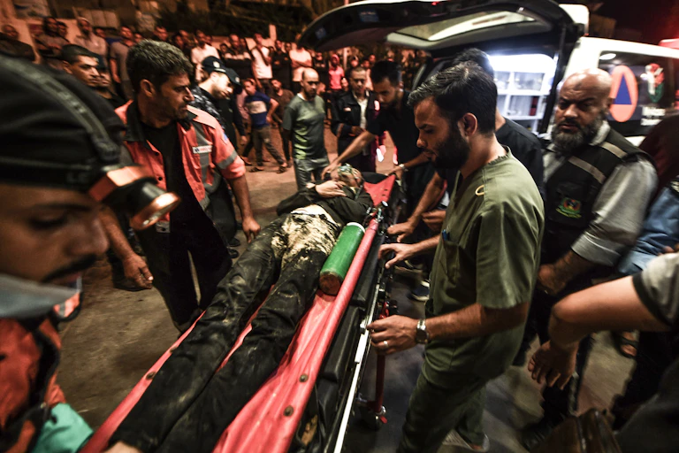 A man on a gurney is carried by health workers into an ambulance.