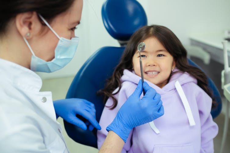 Dentist shows instrument to child patient