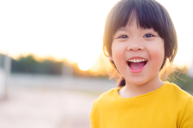 Child wearing a yellow jumper smiles