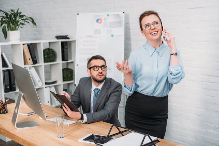 Woman talking on phone distracting colleague who is trying to work