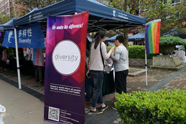People gathered at a stall with signs saying "Diversity"