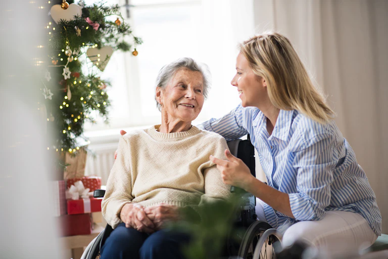 A young woman talks to an old woman next to a Christmas tree.
