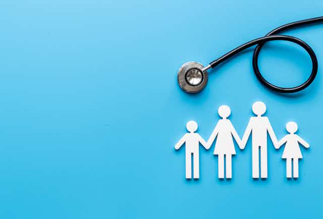A stethoscope over paper cutouts of a family against a blue background