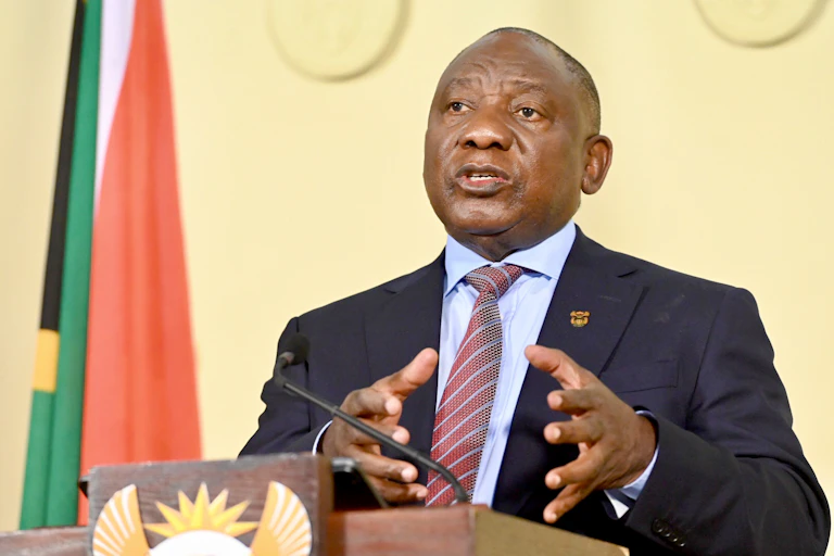A man in a suit speaks at a podium.
