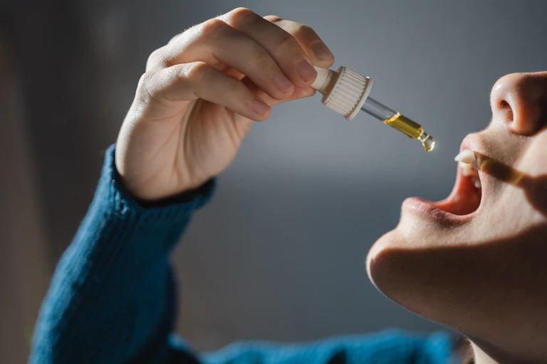 Person holding a dropper containing CBD oil