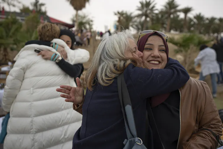 Women smile and embrace each other.