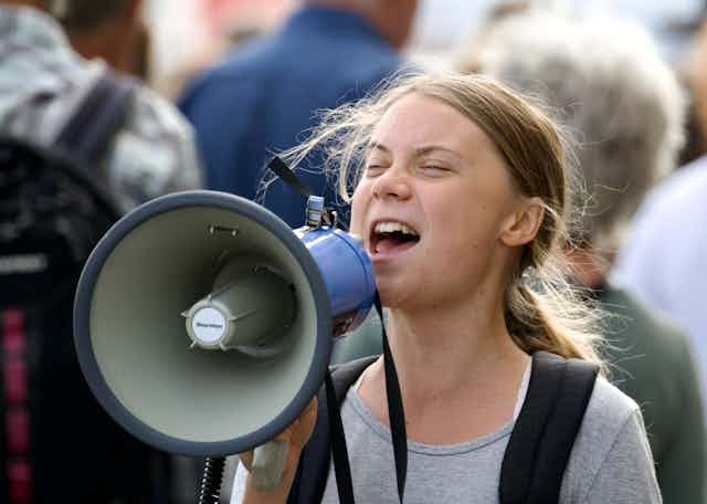Greta Thunberg yells into a megaphone at a demonstration