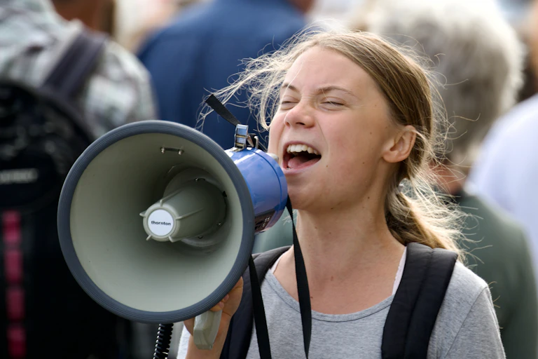 Greta Thunberg yells into a megaphone at a demonstration