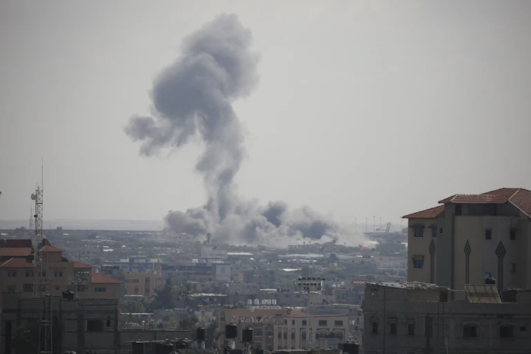 A tall plume of smoke rises above an urban area.