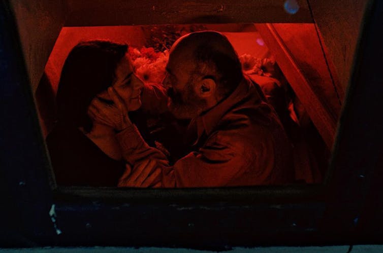 Un hombre sujeta la cara de una mujer mientras ambos se miran.