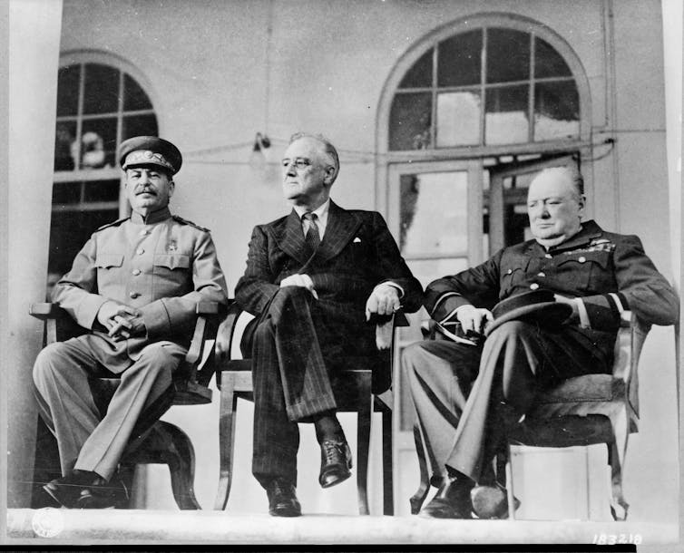 Three world leaders seated side on the porch of a building