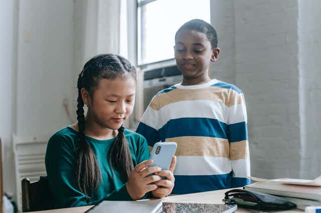 Two students watch a video on a phone.