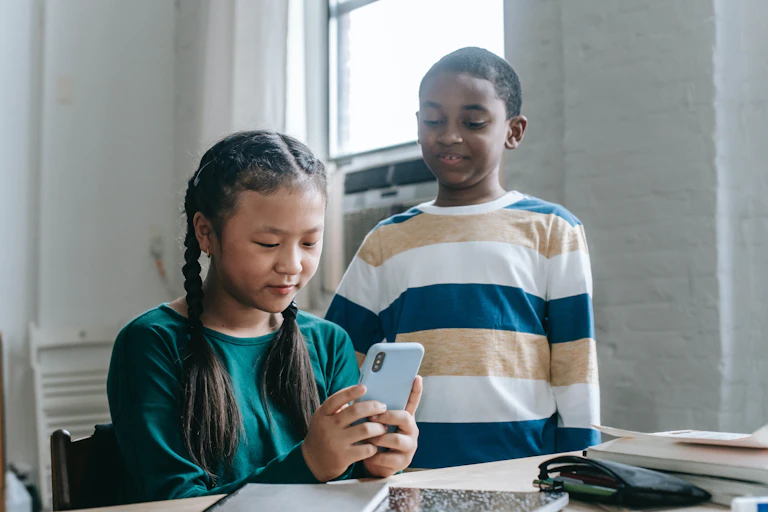 Two students watch a video on a phone.
