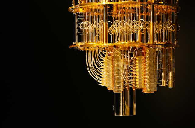 A photo of an elaborate golden machine of loops and wires against a dark background.