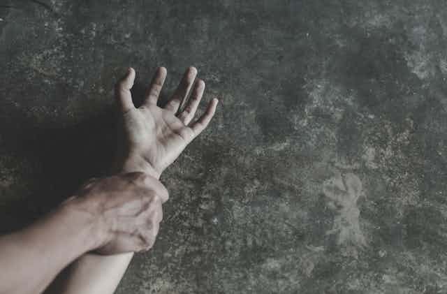 man's hand grips woman's wrist on ground