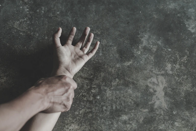 man's hand grips woman's wrist on ground