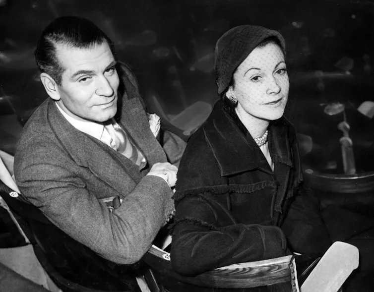 A black and white photo of Vivien Leigh sitting next to Laurence Olivier.