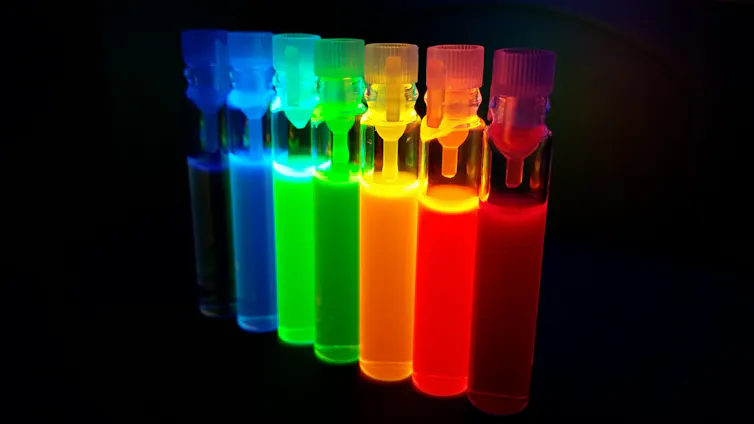 A row of glass testubes with different colours containing quantum dots.