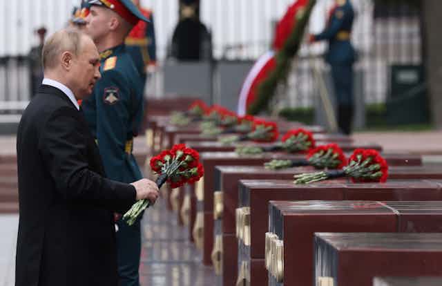 Vladmir Putin lays roses on coffins during a memorial service.