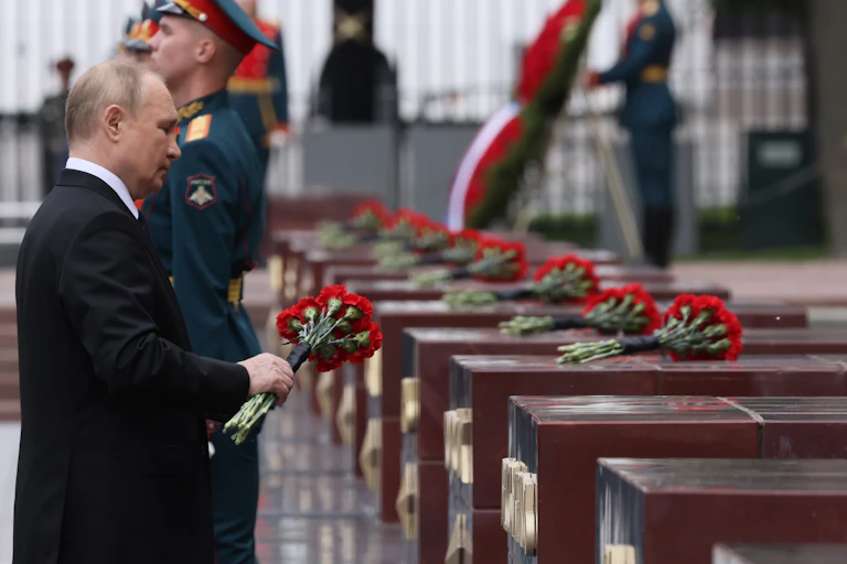 Vladmir Putin lays roses on coffins during a memorial service.
